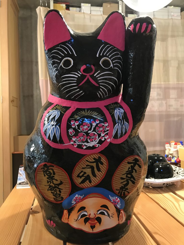 Huge black lucky cat with a face painted on its belly
