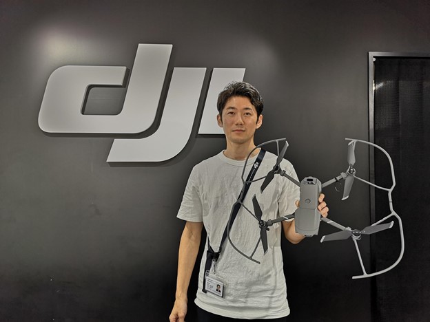 Japanese man holding a drone in front of a DJI sign