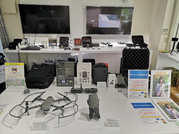 Drones, controllers, cases on display on white tables