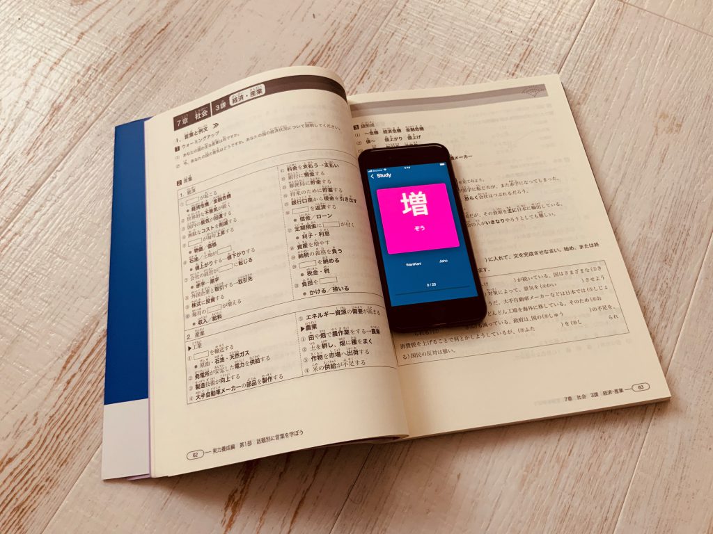 Smarpthone displaying a Japanese language learning app on a Japanese language learning book