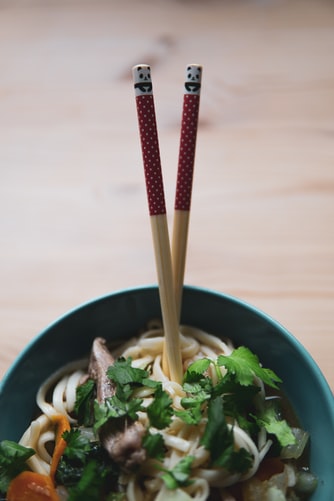 Chopsticks stuck upright in a noodles bowl