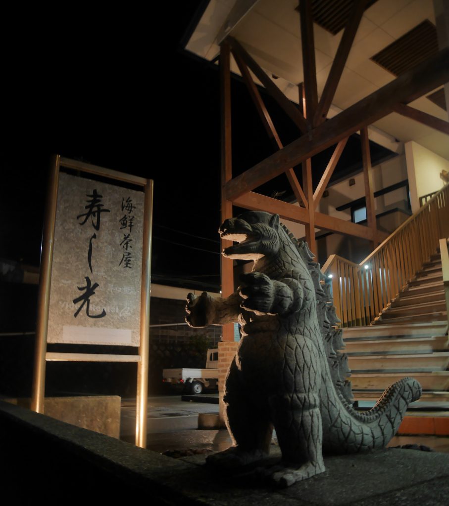 A small Godzilla statue in front of a building