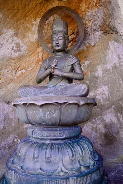A Buddhist statue. The bodhisattva has a crown and is sitting leg crossed