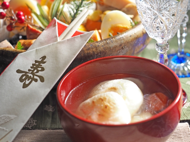 A bowl of soup with two balls of grilled mochi inside