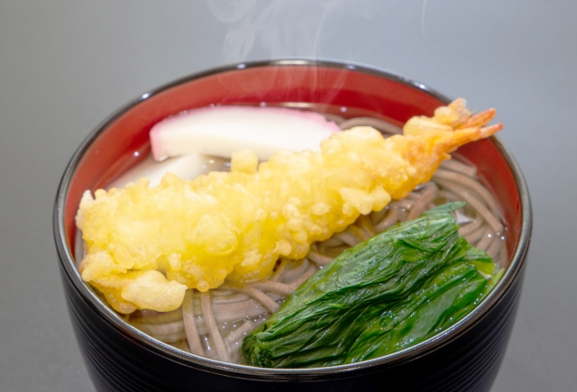 A bowl of buckwheat noodles with a shrimp tempura on top