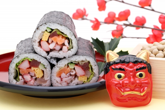 Big sushi rolls on a plate next to an oni mask