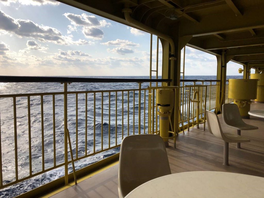 Some chairs and tables on the deck of a boat