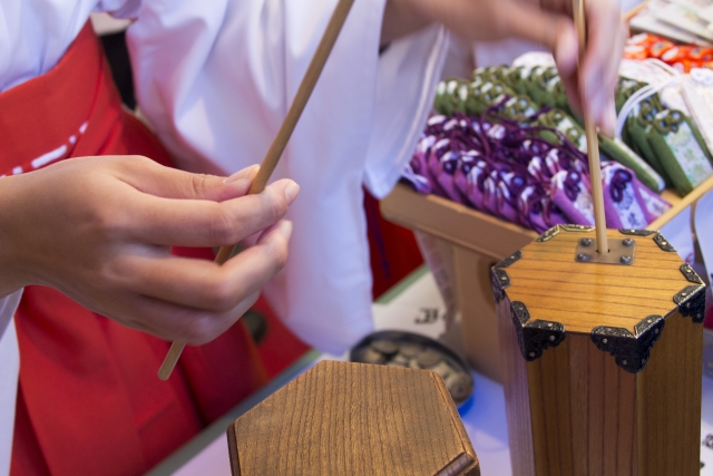 A shrine lady putting the wooden sticks back into the oracle tube.