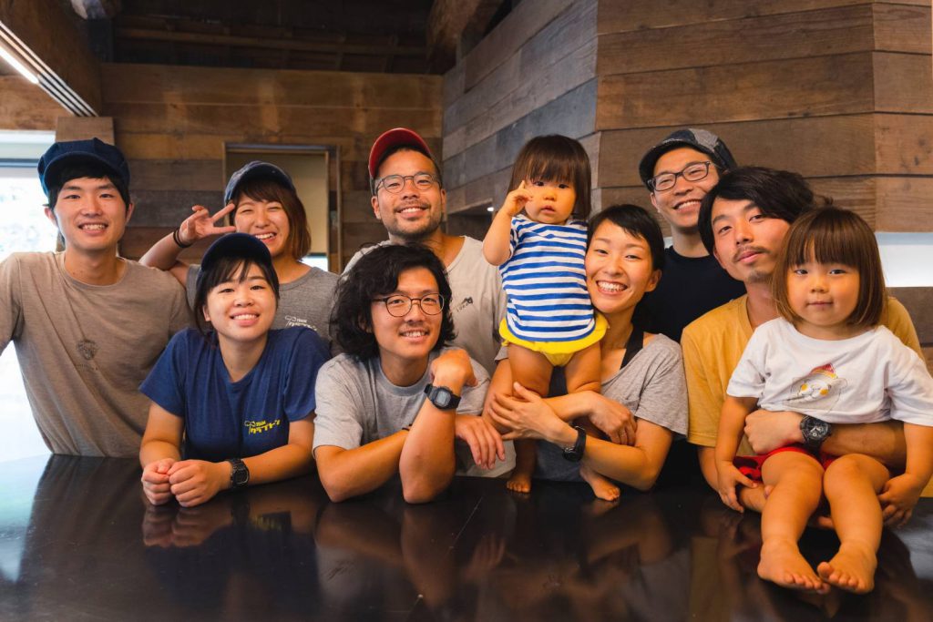 A group of eight adult Japanese people and two kids are smiling at the camera