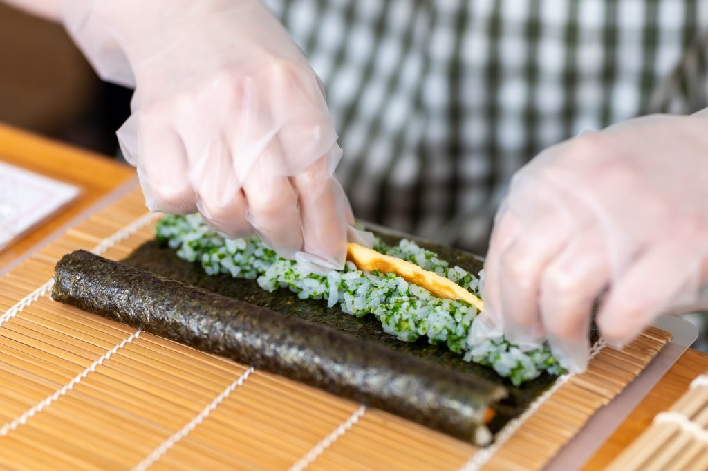 The author is putting rice and other ingredients on wakame seaweed