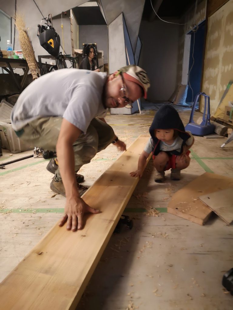 A man and a child touch a wood plank