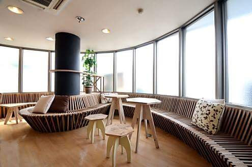 A modern-looking very long bench and some wooden chairs and tables