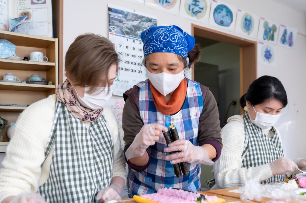 A Japanese woman shows the tips of two sushi rolls to the author