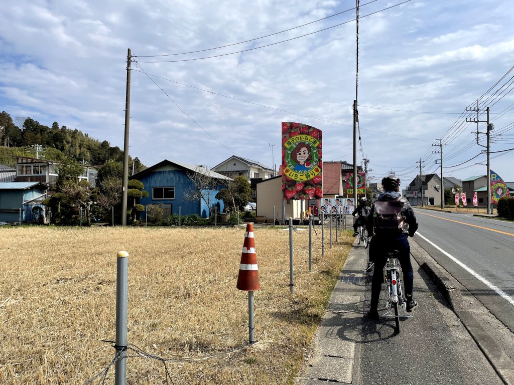 People cycling to the farm. Huge signs with the farm's logo indicate the place.