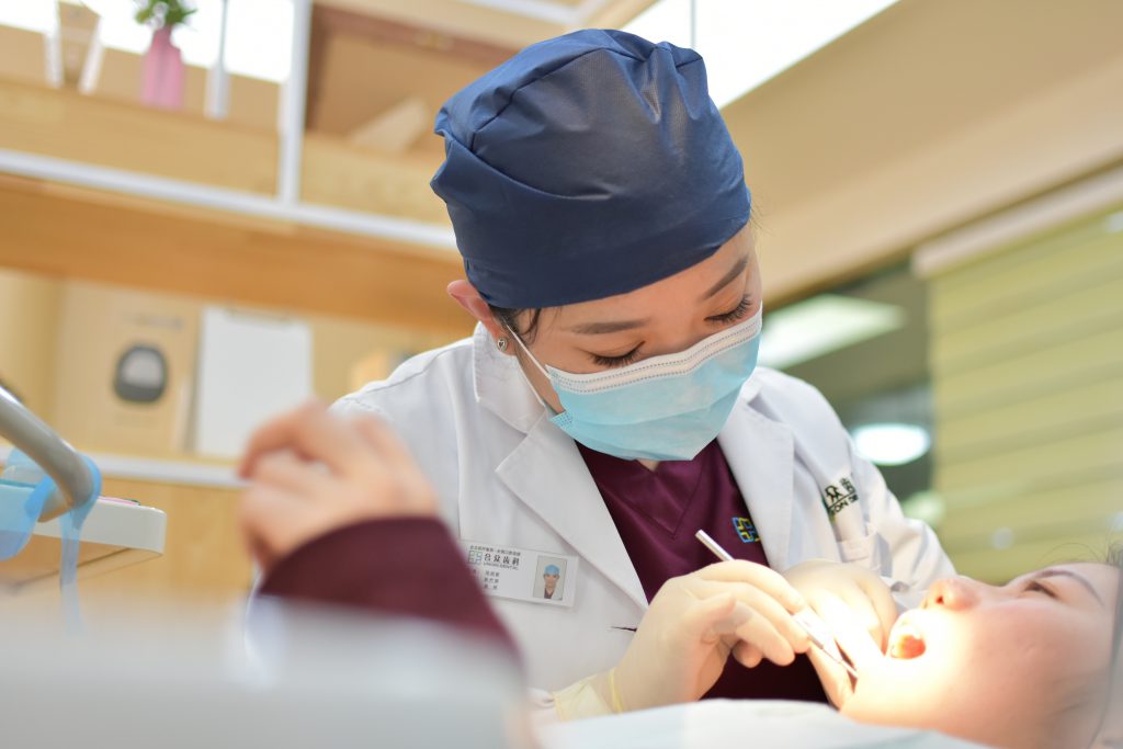 A dentist is looking at her patient's mouth