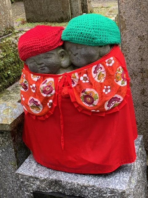 A small statue represents two childish looking figure hugging together. They are covered by a red bib.