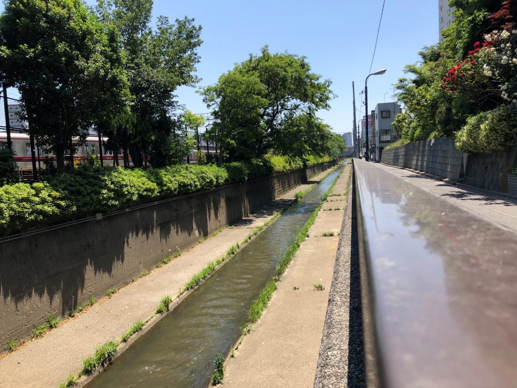 Empty trains can be seen behind a fence on the left of the river.