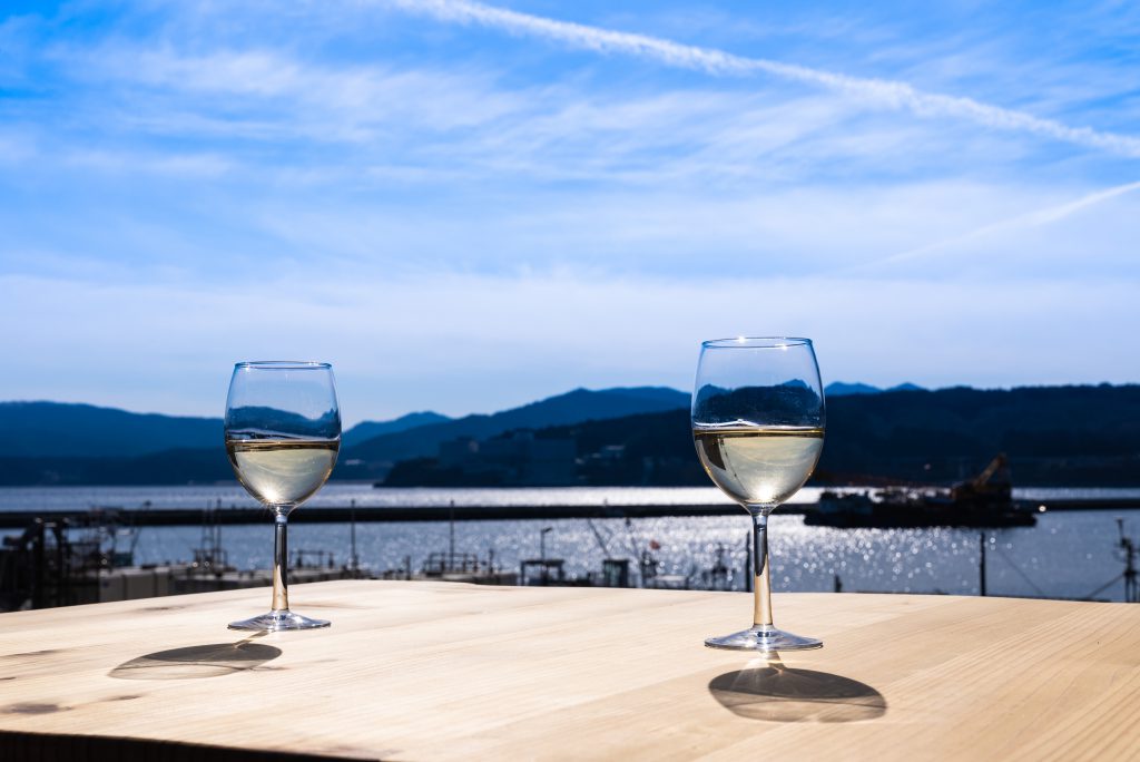 Two glasses of white wine on a table near the sea