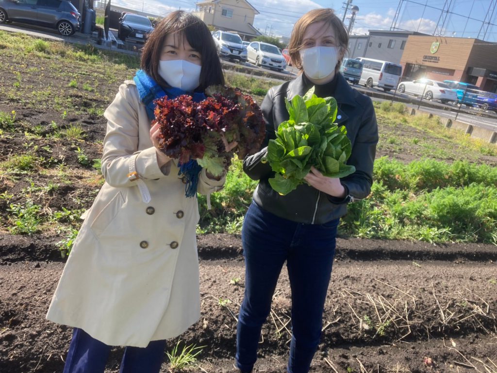 Two women holding vegetables in a field