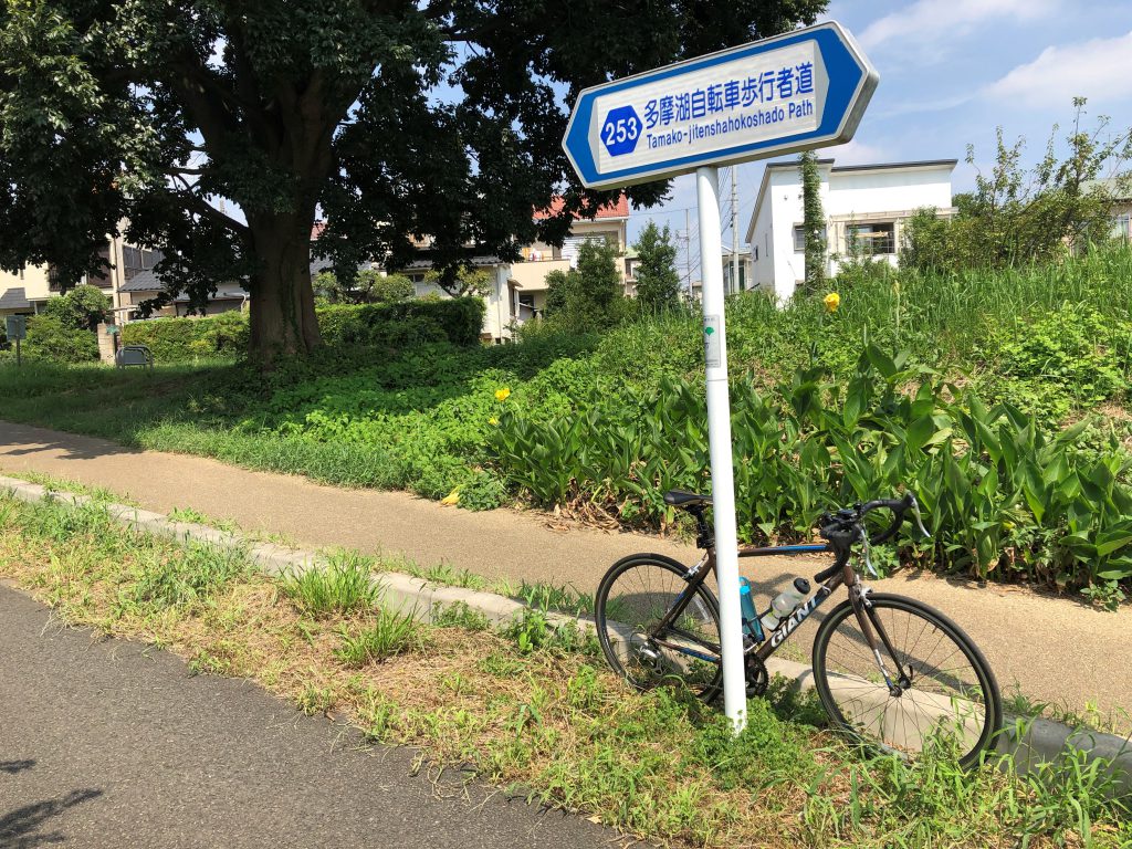 A bicycle is put next to a sign indicating the Tamako cycling road.