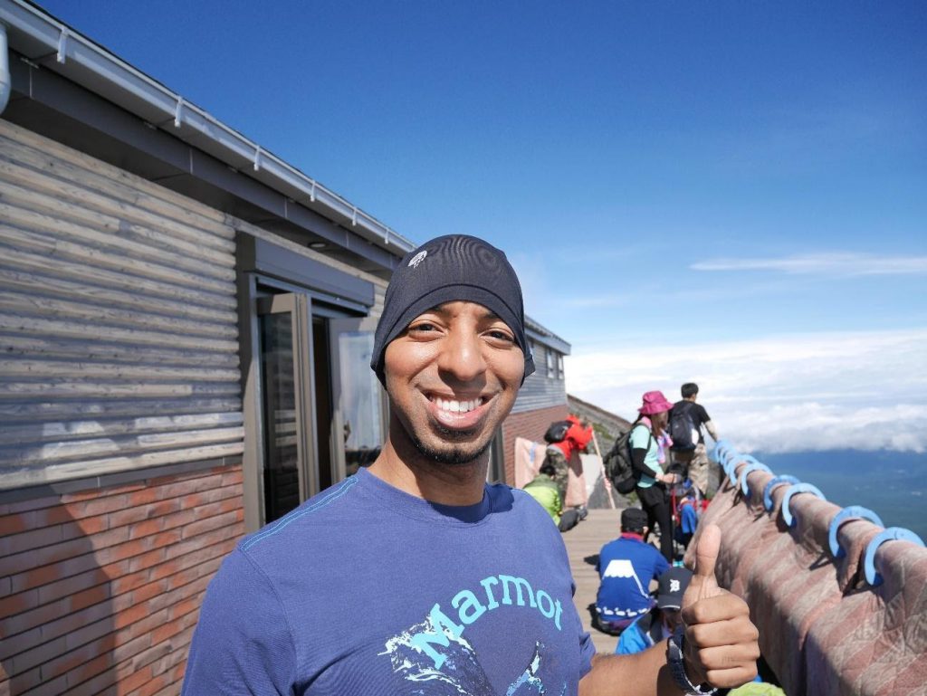 Anthony is smiling on top of a mountain