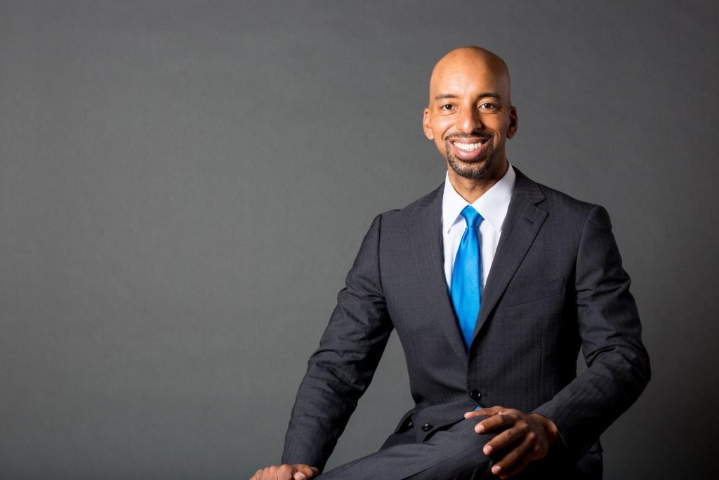 Anthony, dressed in a suit, is smiling to the camera