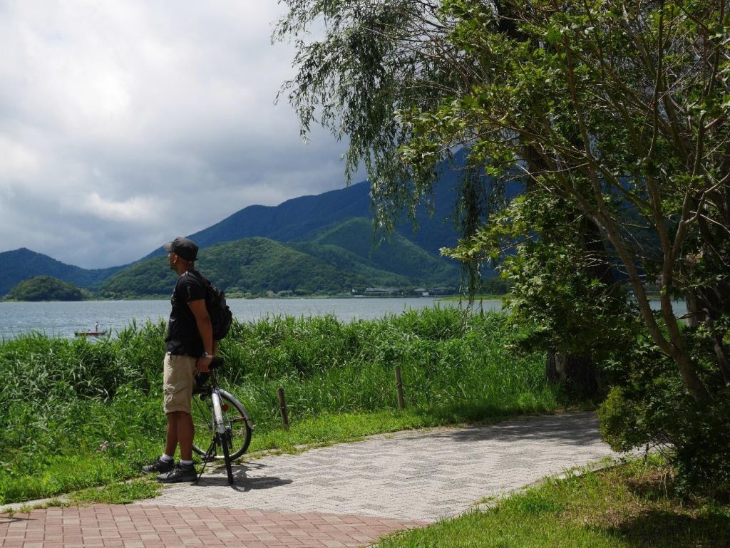 Anthony is looking at the scenery, resting next to his bicycle