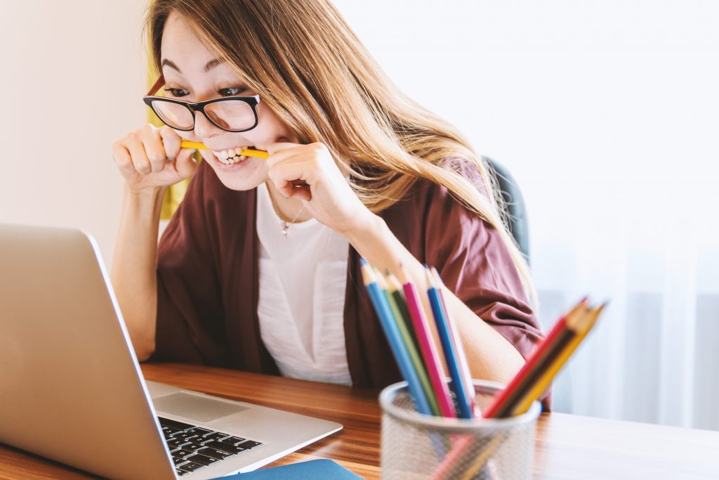 A woman is biting her pencil with frustration while studying