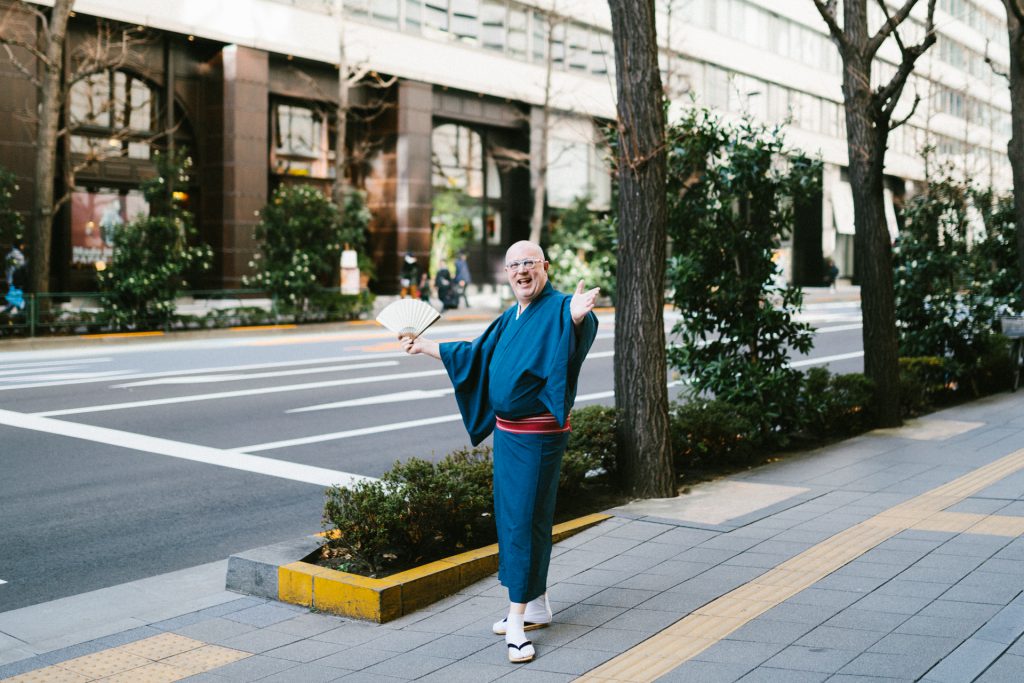 Cyril is posing on an avenue in Tokyo with his folding fan