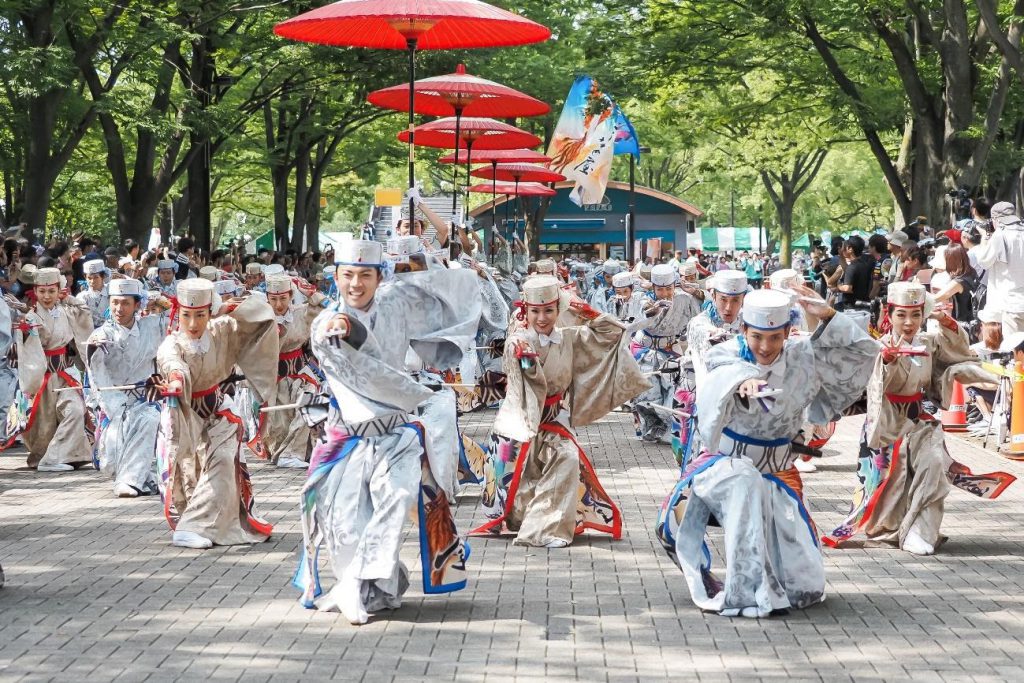 A team of dancers in vivid costumes are dancing in the street,