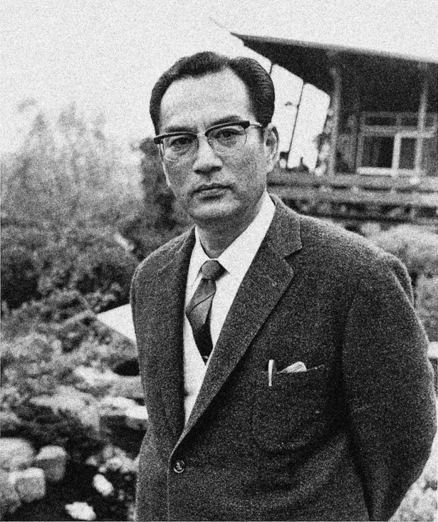 Black and white picture of a Japanese man in an elegant suit and glasses