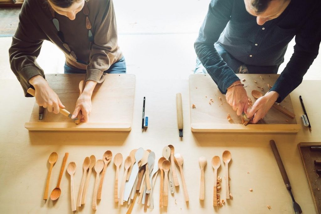 Two bed and craft guests carving spoons.
