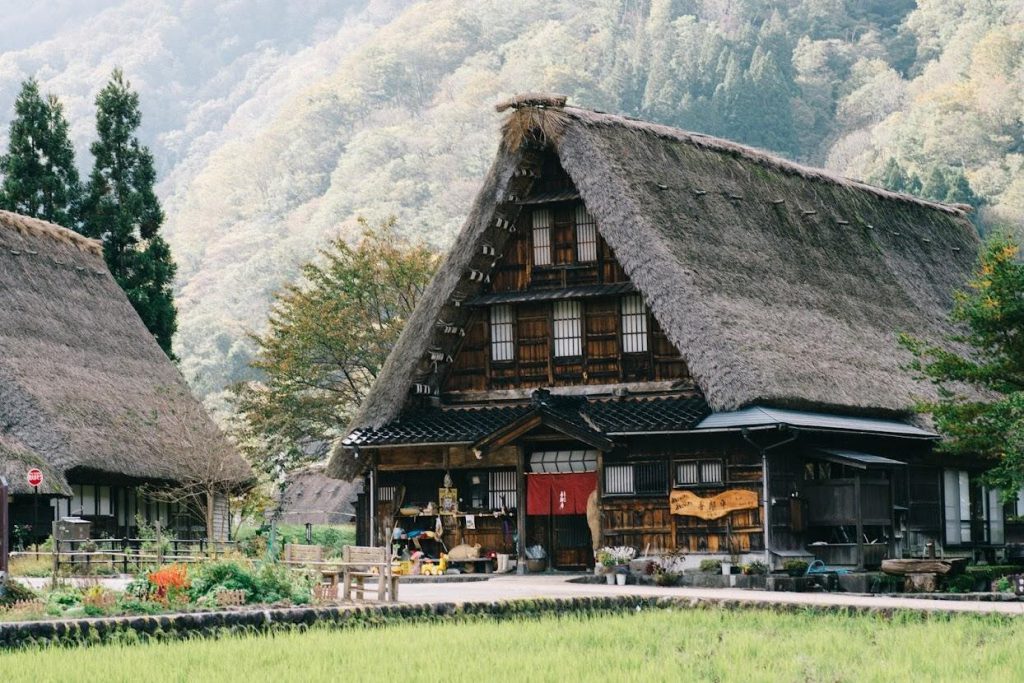 A triangular shaped wooden house with a thatched roof. 