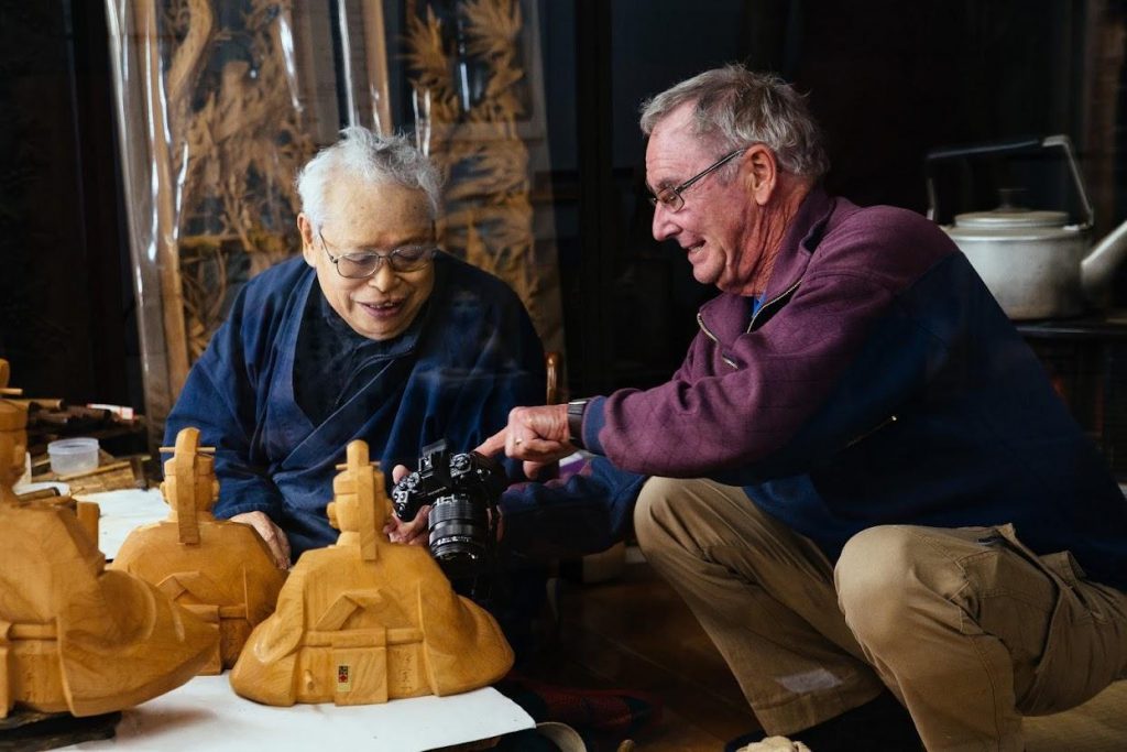 A Western man shows a picture he has taken on his camera to an Inami artisan.