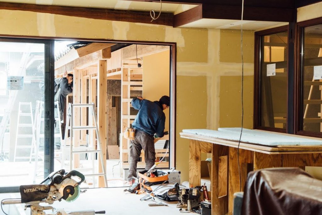 People are working on the walls and pillars of an ancient Inami house.