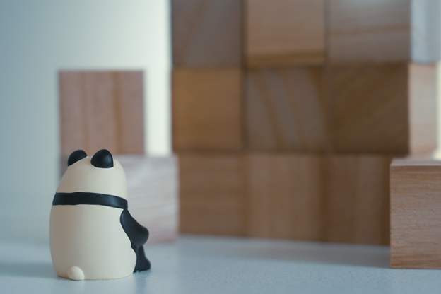 A lonely panda figure is staring at a wall.