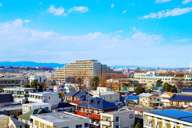 A picture of a Japanese city shows two-stories in the foreground, and multiple stories buildings in the background.