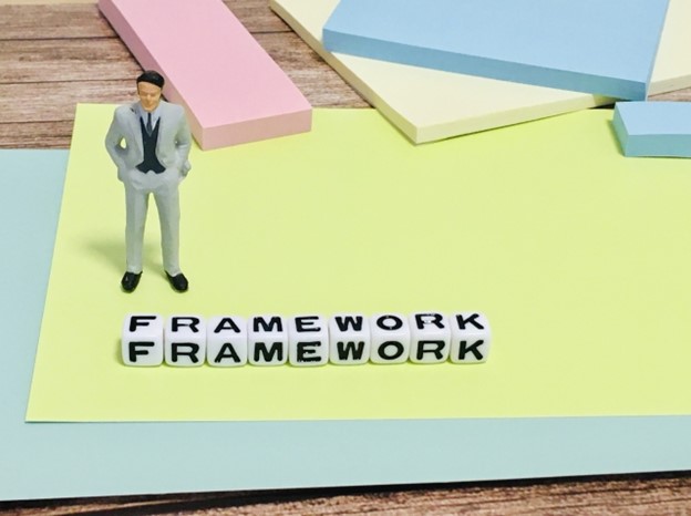 A doll representing a businessman is standing behind the word "framework"