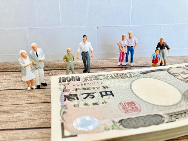 Tiny dolls representing different family members are standing next to banknotes.