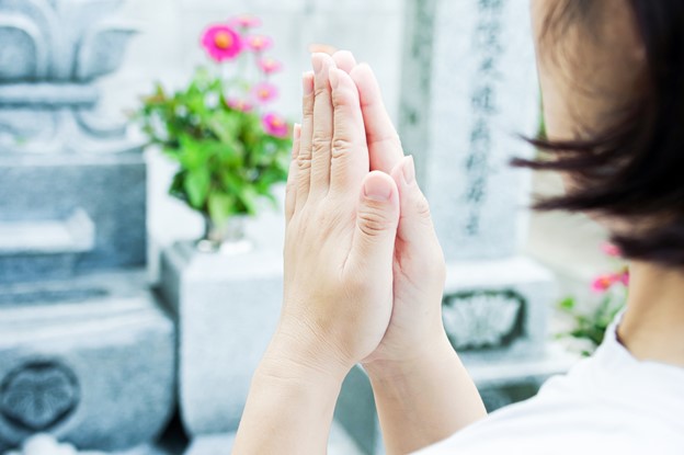 A woman is praying in front of a tomb.