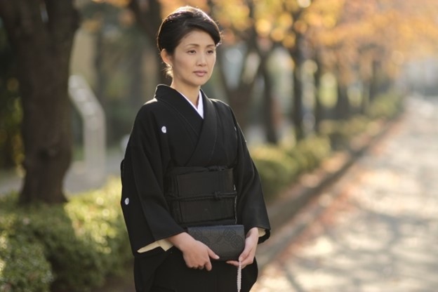 A Japanese widos is dressed in a black kimono.