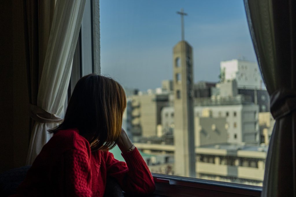 A woman at a window is looking at Tokyo streets pensively