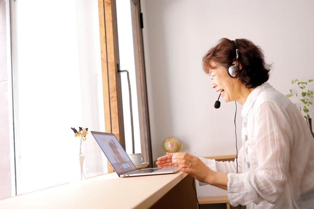 An elderly woman is smiling and talking online