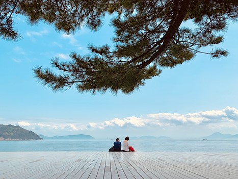 People are sitting on the Japanese seaside. 