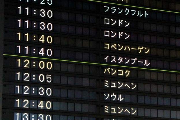 An airport sign shows the name of different cities written in katakana.