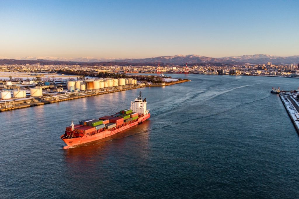 A huge container boat is leaving a Japanese port.