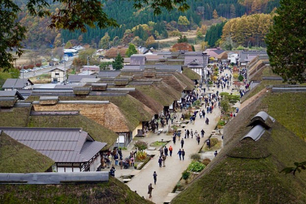 Long houses with thatched roofs are aligned along a pedestrian street