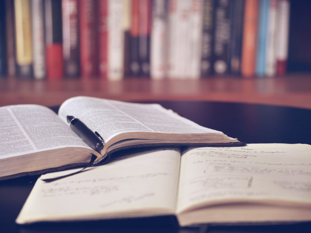 A dictionary, a notebook, and a pen are on a tabke