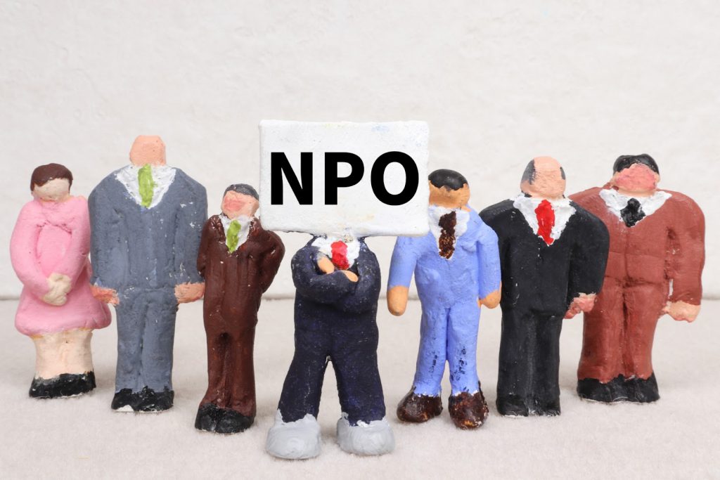 Clay figures representing people in business suits gather around one character whose head is a sign that says "NPO"