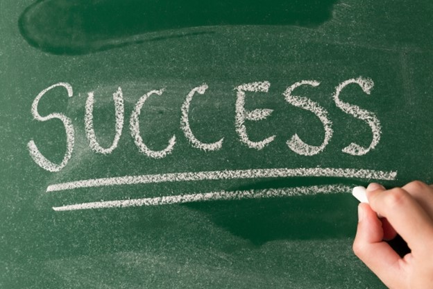 The word "success" is written with a chalk on a blackboard and underlined twice.
